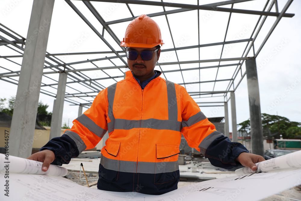 Portrait confident construction engineer wear orange vest and orange helmet with blueprint at construction site.Professional and industry, builder architect job, worker checking work at plant outdoor. Portrait confident construction engineer wear orange vest and orange helmet with blueprint at construction site.Professional and industry, builder architect job, worker checking work at plant outdoor.