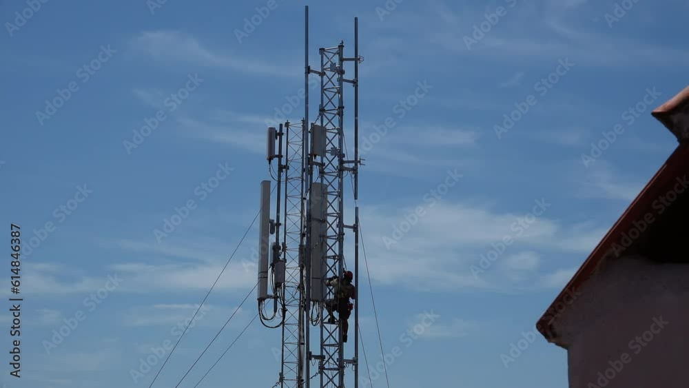 Antenna Tower Technician Climbing Risky Job. Male worker fixing an