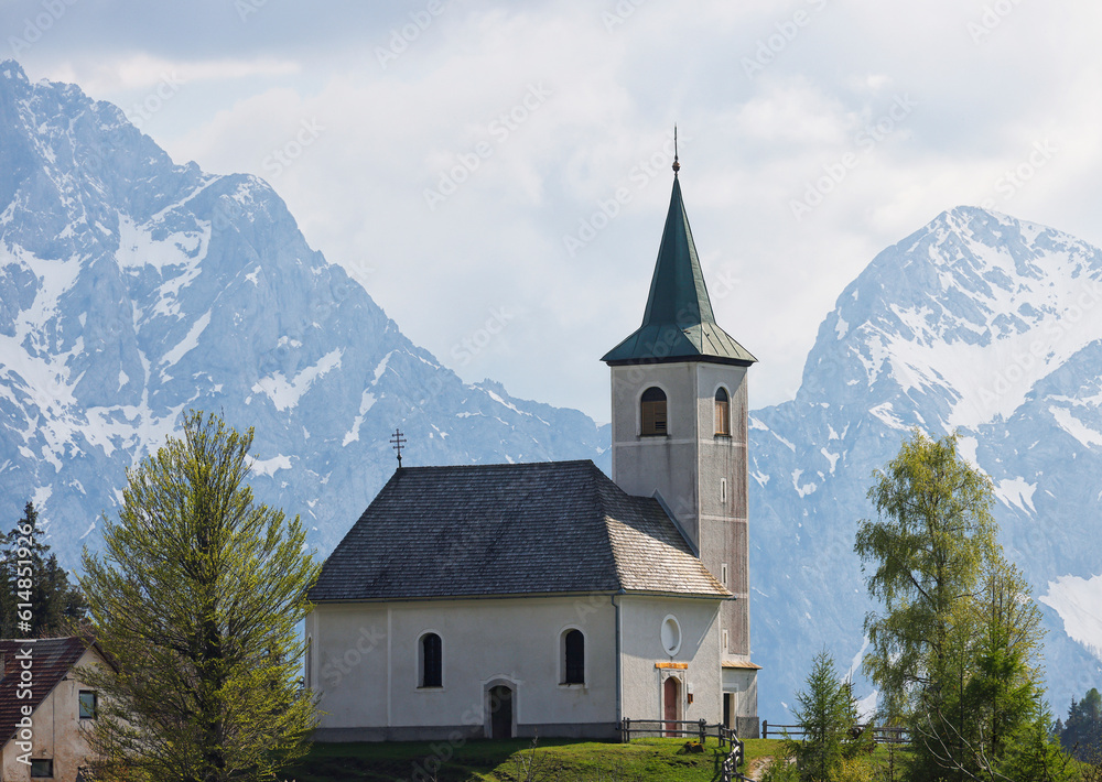 Slovenian mountain landscape and cute small church on the hill. St Spirit ( Sveti Duh) church and Kamnik-Savinja Alps in background, Slovenia, Europe