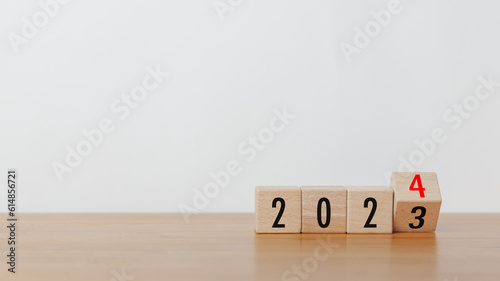 Wooded cube block flipping from 2023 to 2024 text on wooden table with white background. New year goal, action plan, business plan, finance and marketing strategy concept.
