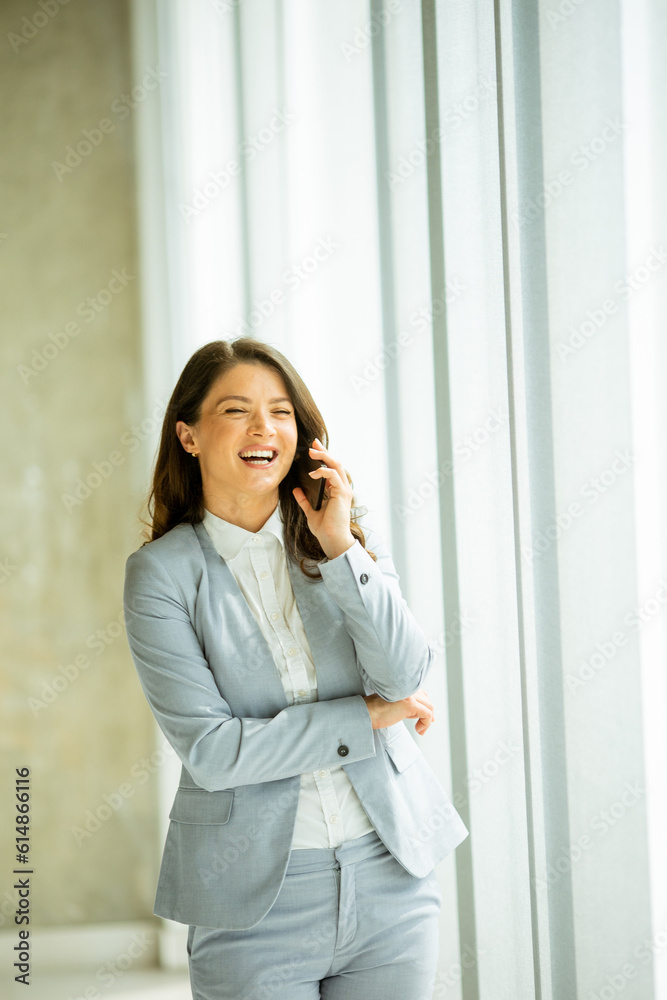 Young woman using mobile phone by the office window Young woman using mobile phone by the office window