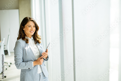 Young woman working on digital tablet by the office window © BGStock72