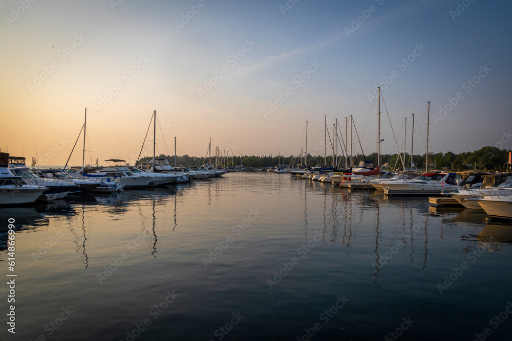 Boats are neatly lined up in a row in the harbour in Port Elgin, Ontario during a late evening sunset.