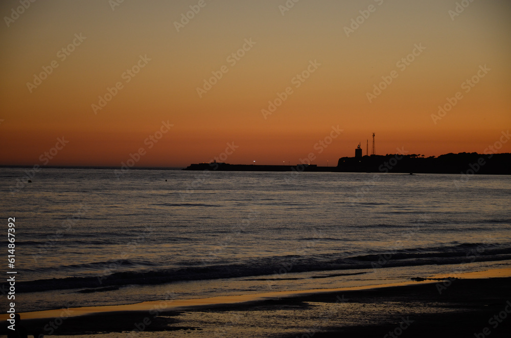 Colorful sky at sunset on the coast of Conil in Spain, looking at the lighthouse on the rocky coastline