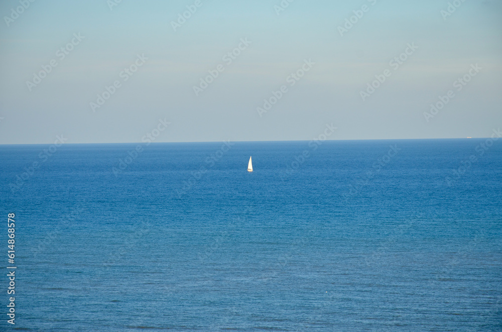 A lonely sailboat on the horizon of the Mediterranean ocean
