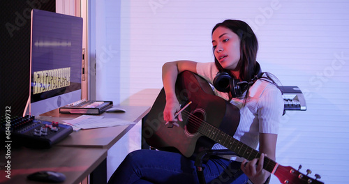 Foto Young Asian woman holding guitar composing a song