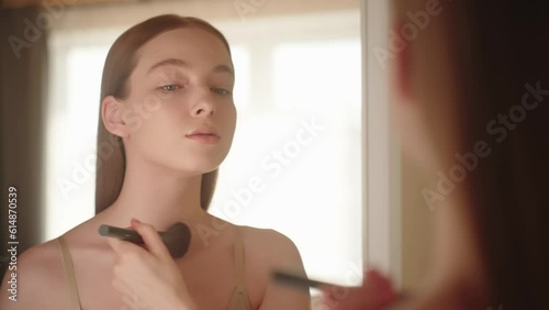 Reflection Happy beautiful young blonde woman applies powder on face