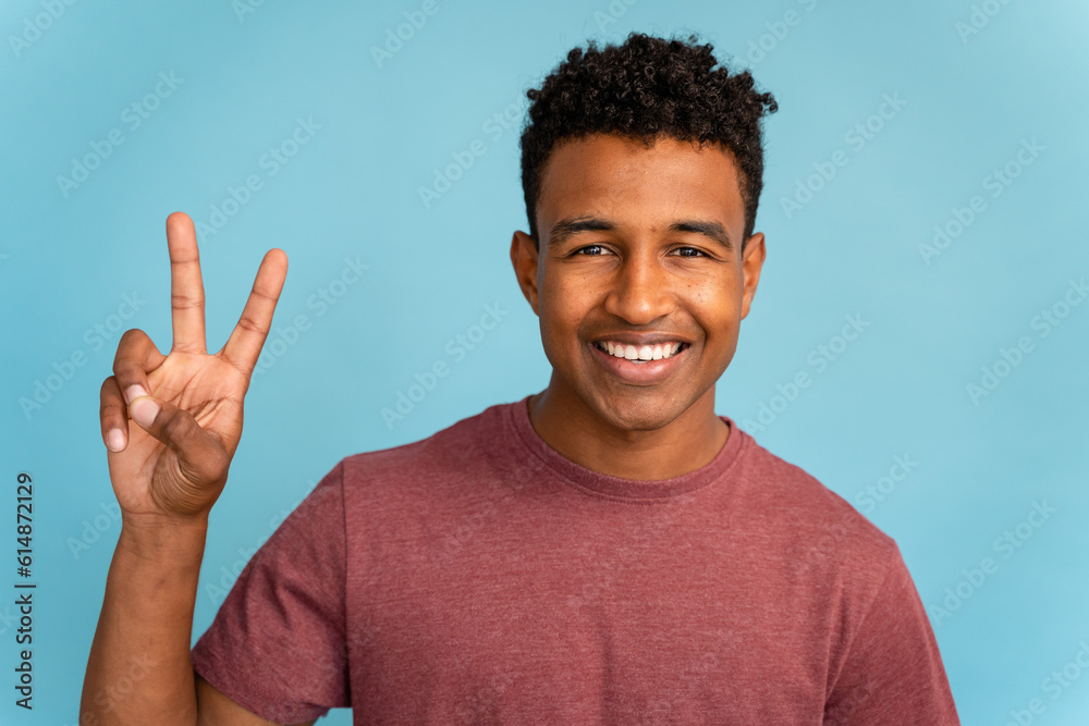 Smiling young man making peace sign with fingers. Smiling young man making peace sign with fingers.