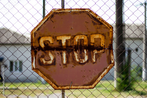 rusty metal warning sign on fence