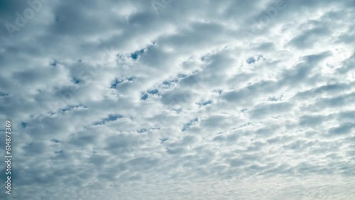 White altocumulus clouds in the rays of the morning sun. The movement of fluffy clouds crossing the blue sky. Summer timelapse.