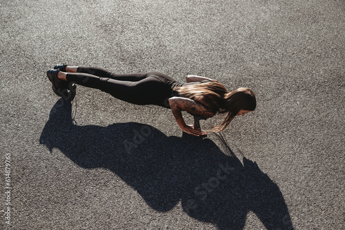 Beautiful young fit tanned caucasian woman exercising outdoors