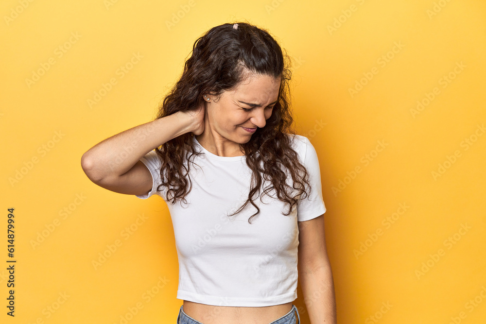 Young Caucasian woman, yellow studio background, suffering neck pain due to sedentary lifestyle. Young Caucasian woman, yellow studio background, suffering neck pain due to sedentary lifestyle.