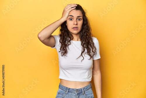 Young Caucasian woman, yellow studio background, being shocked, she has remembered important meeting.