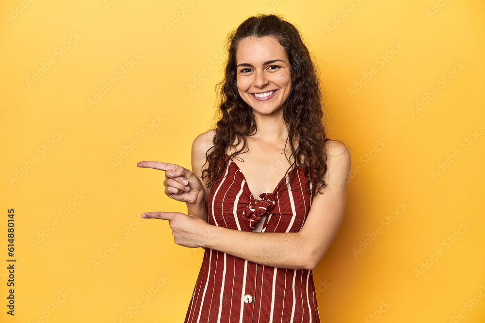 Young Caucasian woman, yellow studio background, excited pointing with forefingers away. Young Caucasian woman, yellow studio background, excited pointing with forefingers away.