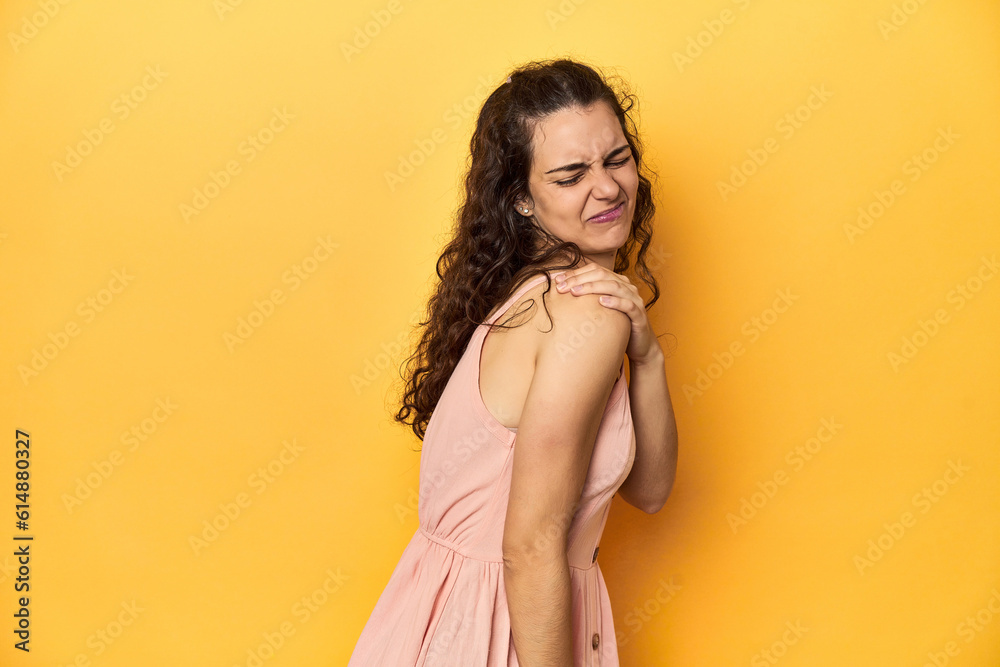 Fototapeta premium Young Caucasian woman, yellow studio background, having a shoulder pain.