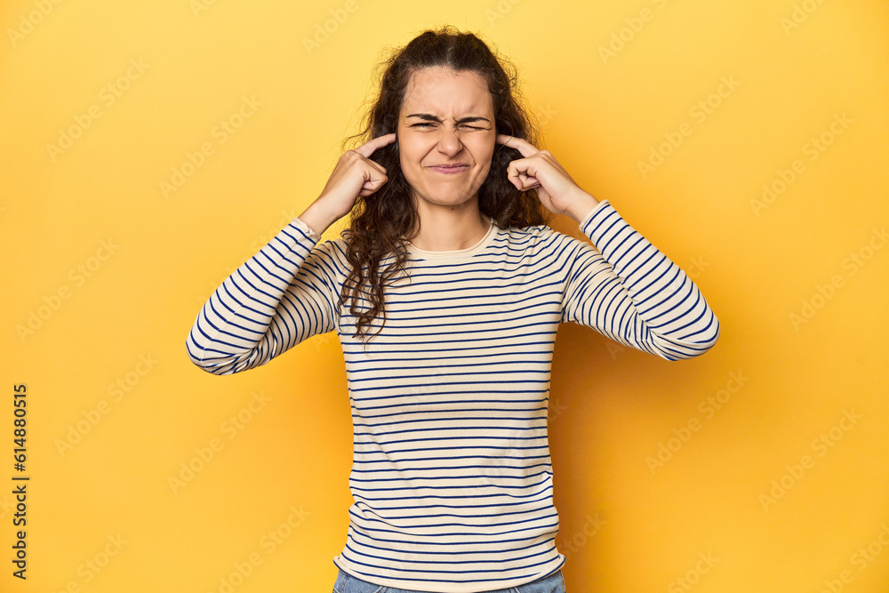 Young Caucasian woman, yellow studio background, covering ears with fingers, stressed and desperate by a loudly ambient. Young Caucasian woman, yellow studio background, covering ears with fingers, stressed and desperate by a loudly ambient.