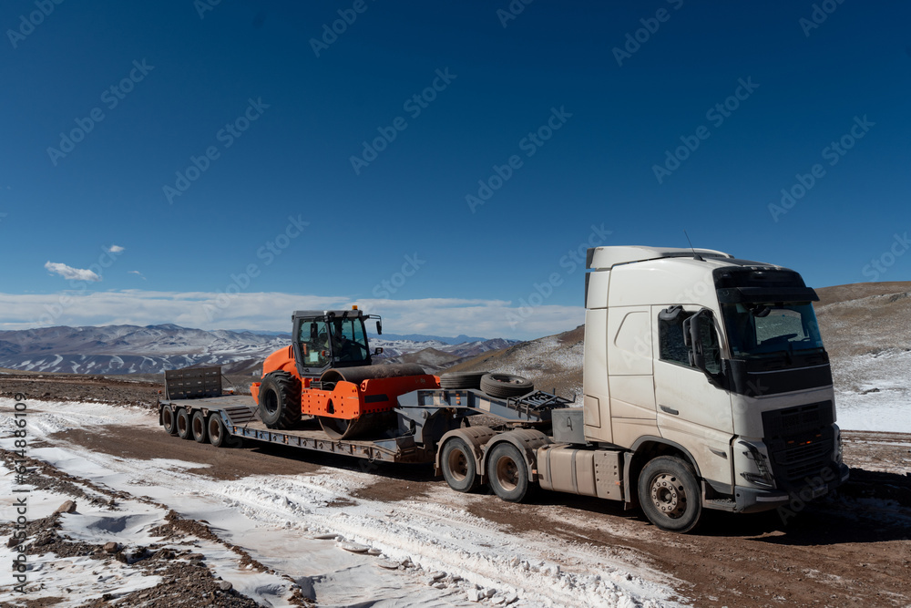 Truck transporting machinery to open roads in the snow-covered mountains