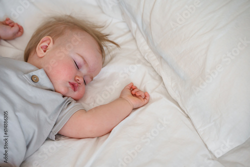 Cute caucasian child toddler sleeps on white sheets