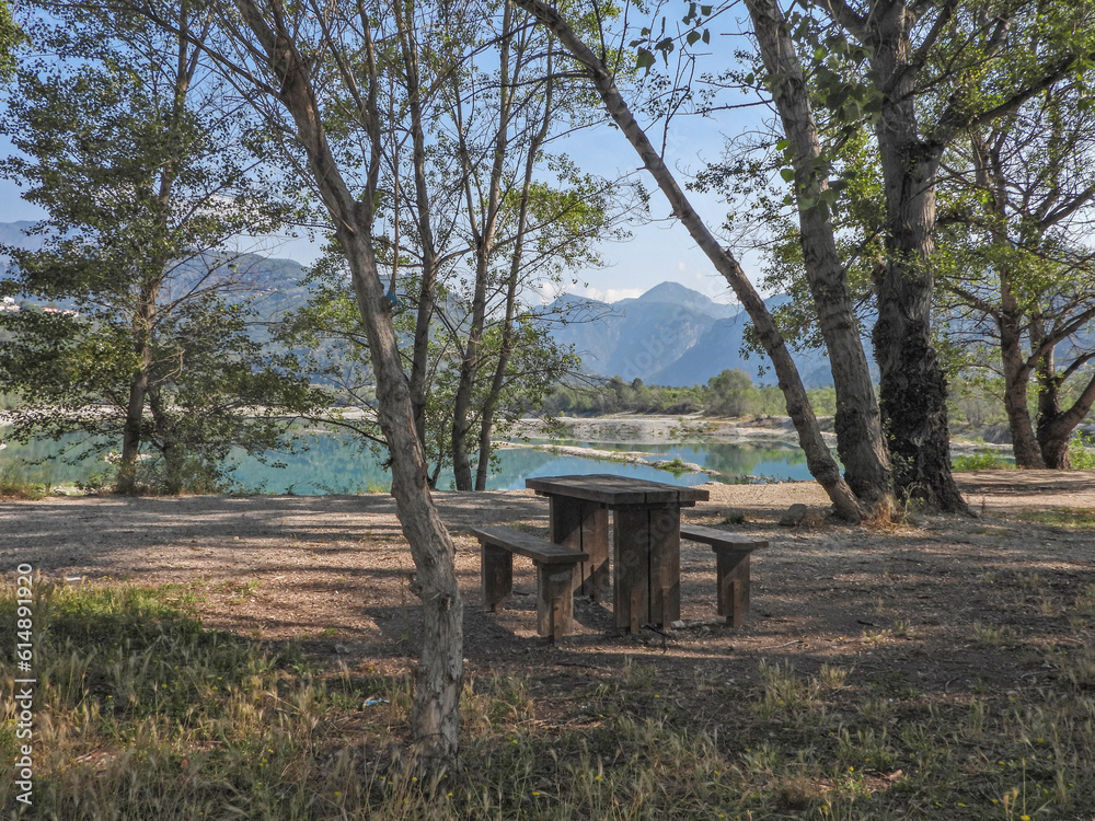 Paysage au bord d'un lac entouré de montagnes avec une table et des bancs en bois au premier plan