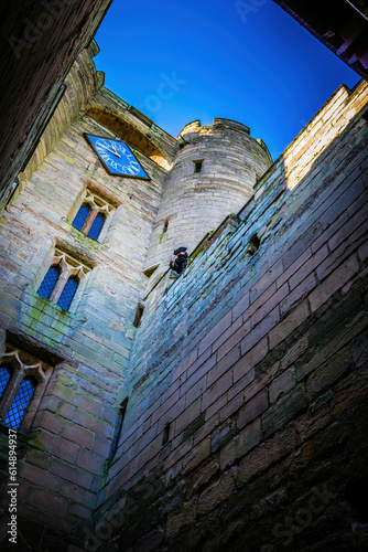 Inner courtyard of a castle with an actor hanging over the wall.