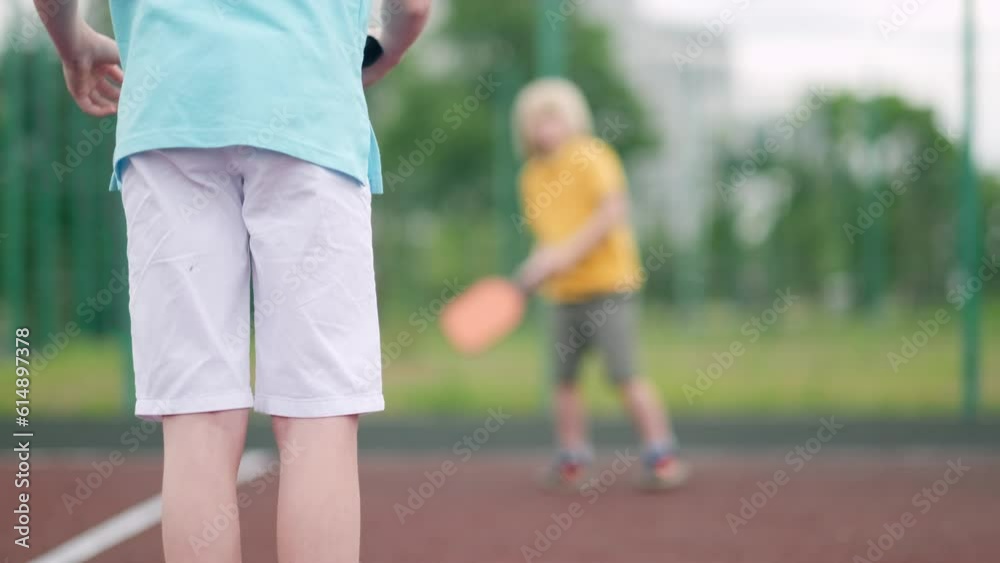 close up kids playing pickleball game, hitting pickleball yellow ball with paddle, outdoor sport leisure activity. close up kids playing pickleball game, hitting pickleball yellow ball with paddle, outdoor sport leisure activity.