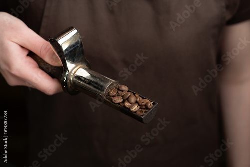 Kaffeebohnen Probenzieher wird in der Hand gehalten, geröstete Bohnen werden gezeigt photo