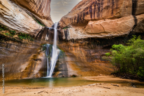 Vertical waterfall that flows into a small green lake. Upper Calf Creek Falls Capitol Reef National Park Utah. Located in south-central Utah in the heart of red rock country, Capitol Reef National Par