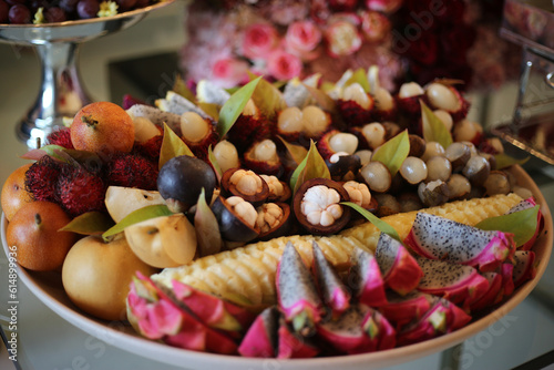 Fototapeta Naklejka Na Ścianę i Meble -  Uma bela seleção de frutas frescas, incluindo mangostin, maçã verde, pitaia e lichia, disposta de forma elegante em uma mesa de sobremesas durante um evento sofisticado.