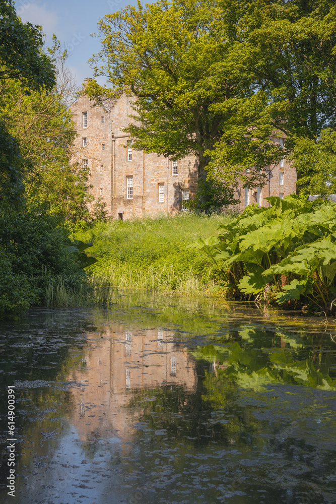 The historic Kellie Castle and gardens reflected in a pond on a sunny summer day in East Neuk, Fife, Scotland, UK.
