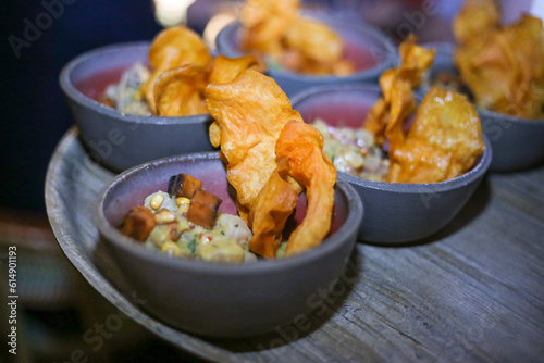 Ceviche de peixe com cubos de abóbora e chips de batata doce, servido em um bowl de cerâmica artesanal. photo