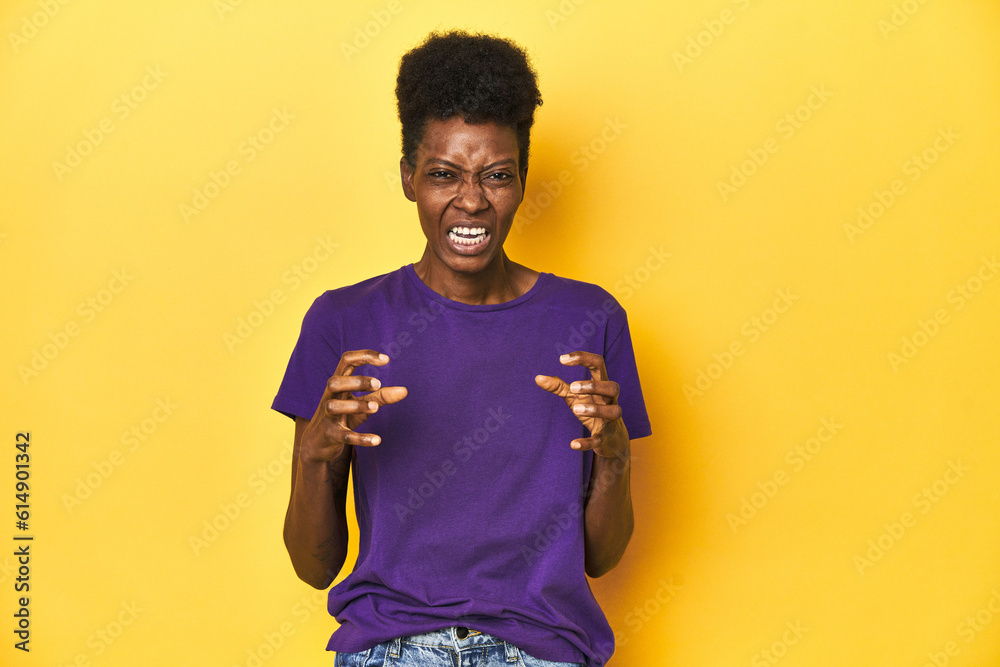 African woman in violet tee, yellow studio scene, screaming with rage. African woman in violet tee, yellow studio scene, screaming with rage.