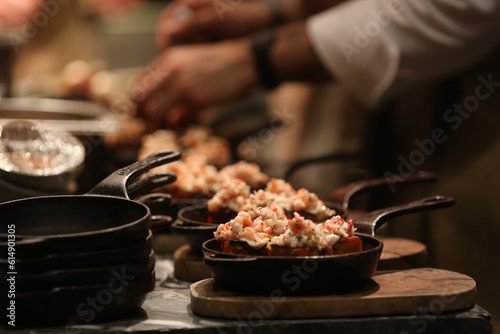 Mãos habilidosas de um chef finalizando uma série de bruschetas de ceviche de peixe branco, que serão servidas em dupla, em charmosas panelinhas de ferro, durante um evento realizado em um restaurante photo