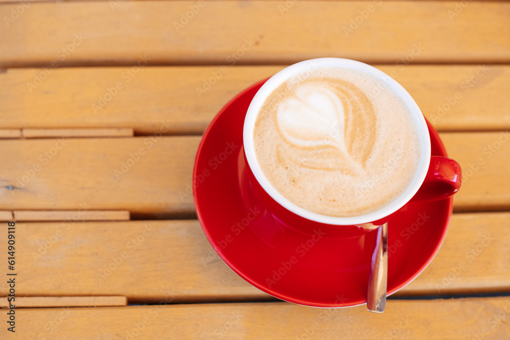 Obraz premium Red cup, Latte coffee heart-shaped on wooden table backdrop or background, Concept For relaxing