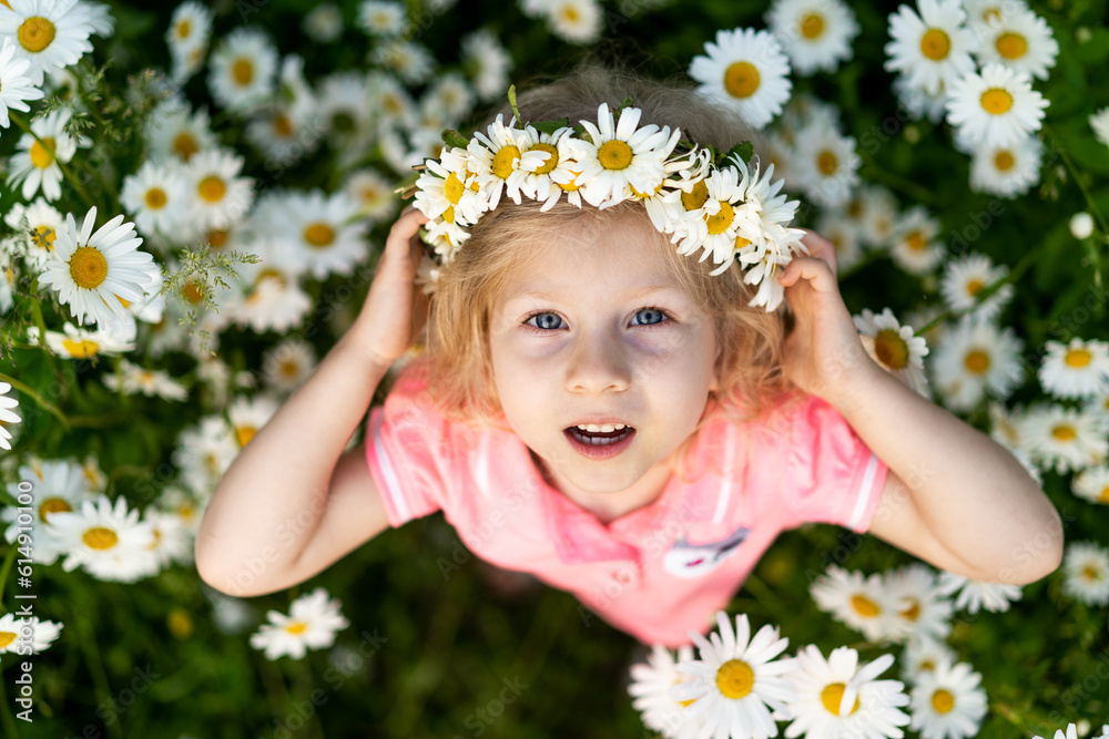 Little happy girl in daisies, close-up portrait on top, child smiling Little happy girl in daisies, close-up portrait on top, child smiling
