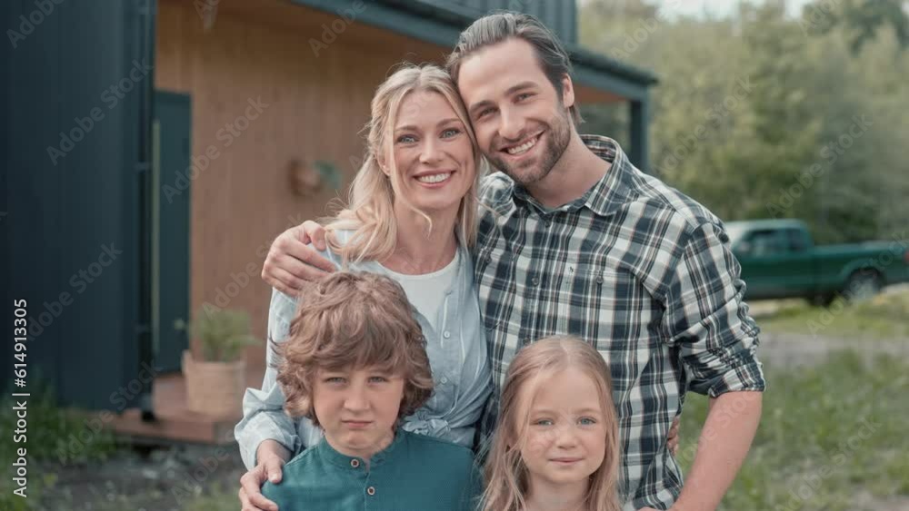 Portrait of beautiful Caucasian family standing in front of camera and joyfully smiling. Happy people spending time outdoor. Loving parents hugging their little children. Resting together in garden. Portrait of beautiful Caucasian family standing in front of camera and joyfully smiling. Happy people spending time outdoor. Loving parents hugging their little children. Resting together in garden.