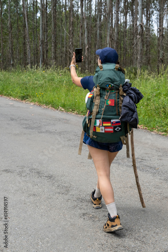 Young woman pilgrim taking a selfie on a trail of the way of saint james. Camino de Santiago. Vertical shot. photo