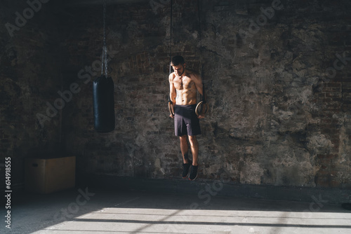 Sportive man exercising gymnastic rings position in fitness studio