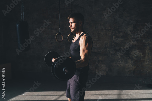Muscular sportsman with heavy barbell weightlifting