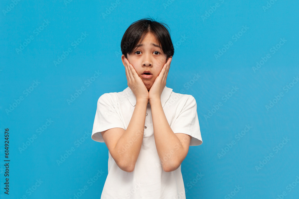shocked asian schoolboy of twelve years old is surprised and worried on blue isolated background, shocked asian schoolboy of twelve years old is surprised and worried on blue isolated background,