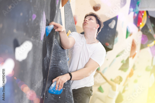 Confident male mountaineer climbing artificial rock wall without belay indoors