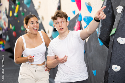 Young sports woman and young teen guy posing near training wall at climbing wall