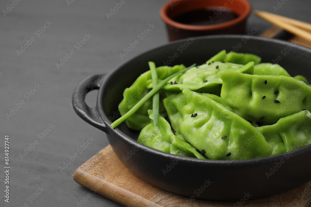 Delicious green dumplings (gyozas) and soy sauce on grey wooden table, closeup. Space for text Delicious green dumplings (gyozas) and soy sauce on grey wooden table, closeup. Space for text