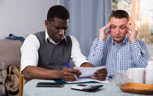 Worried businessmen with phone in home interior filling up documents
