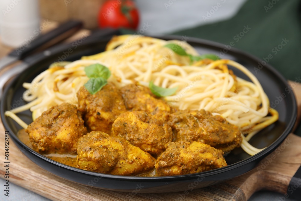Delicious pasta and chicken with curry sauce served on table, closeup