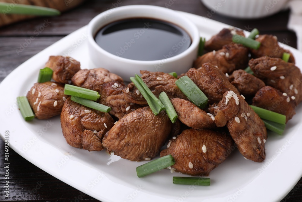 Plate with tasty soy sauce, roasted meat, sesame and green onion on table, closeup Plate with tasty soy sauce, roasted meat, sesame and green onion on table, closeup