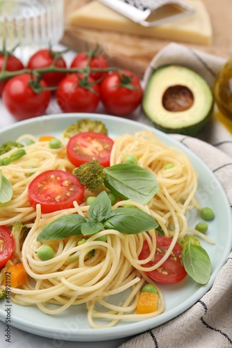 Plate of delicious pasta primavera and ingredients on table, closeup
