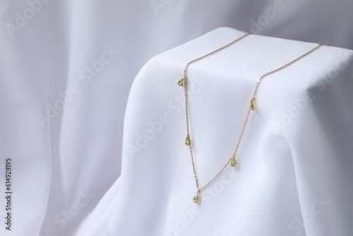 Stylish presentation of necklace on white cloth. Space for text