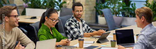 Group of young multiracial business people sitting at desk in the board room and working on project together, discussing work and sharing ideas photo