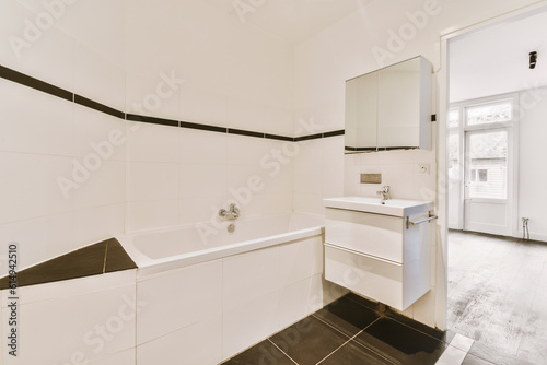 a bathroom with black and white tiles on the walls  sink  mirror and toilet in the room is empty