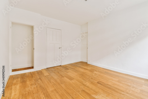 an empty room with white walls and wood flooring on one side, there is a door in the other corner